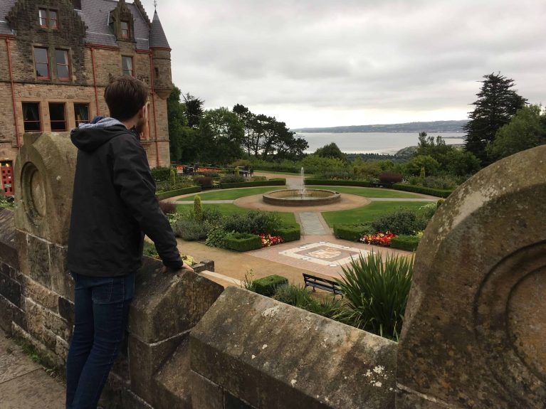 Un jardin adjacent un château de brique rouge.