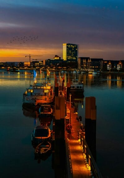 Illuminated harbor with boats at night  in Bremen with the city in the background