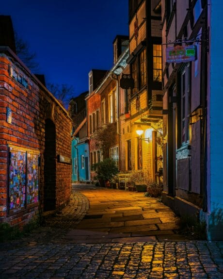 Colorful buildings on a narrow cobblestoned street of Schnoorviertel in Bremen at night featuring gratifies on the doors of a red-bricked wall