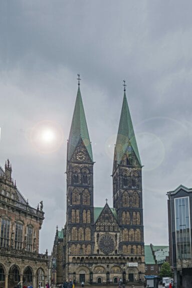 St.Peter’s Cathedral brown bricked building in Bremen with black detailing and its 2 high green-roofed pointed towers on a sunny day