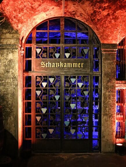 Closeup of the metal door to the treasure chamber, where the most expensive wine is stored, letting a blue light come through in the red-lighted cellars of the Ratskeller in Bremen 