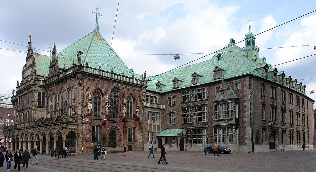 People walking in front of Bremen’s brown-bricked and green-roofed City Hall 