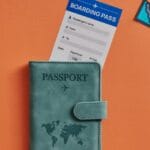 Carte d'embarquement vide et un passeport avec des cartes postales autour sur un fond orange.