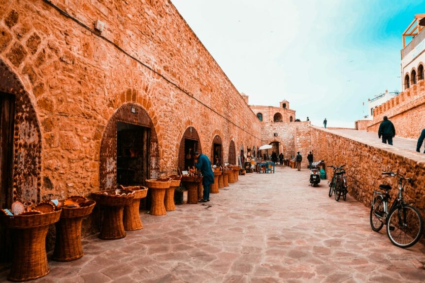 People walking on a street surrounded by brick buildings in Essaouira, Morocco.