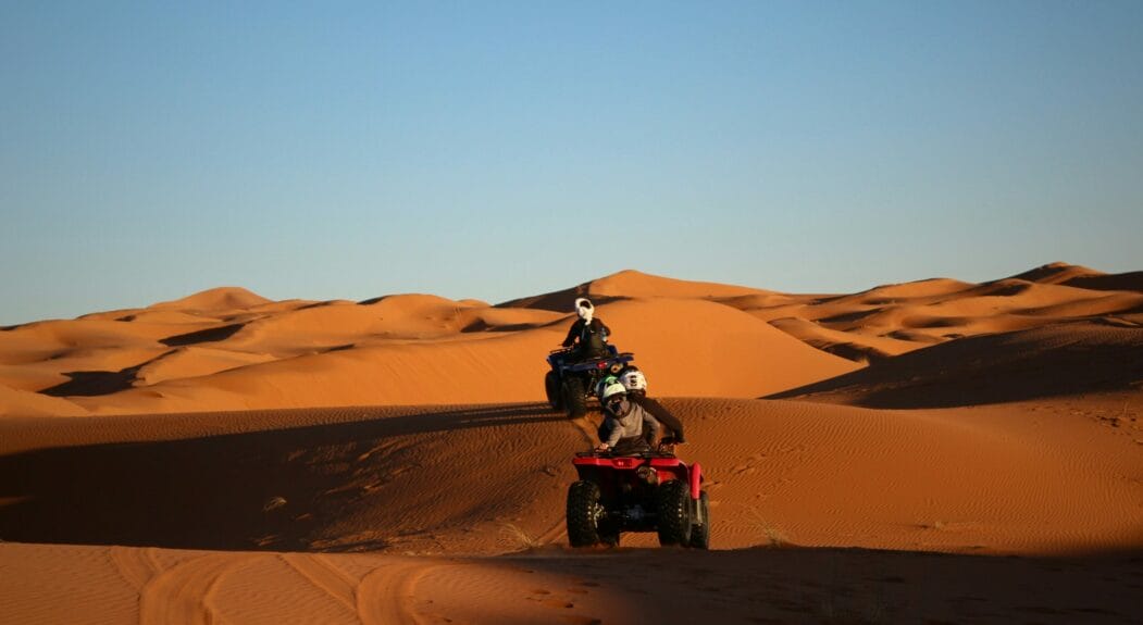 People riding a quad bike in a desert at Merzouga, Morocco.