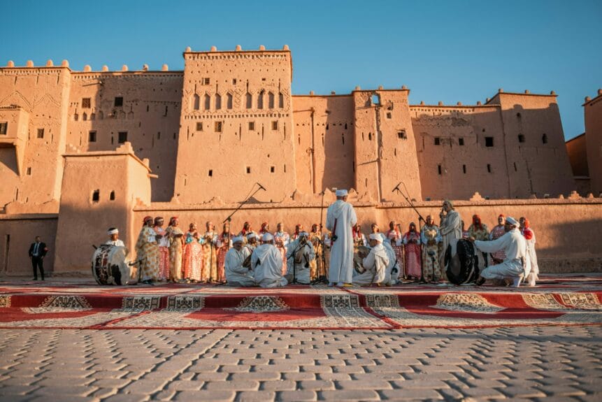 Un groupe de personnes se produisant devant la Kasbah de Taourirt, au Maroc.