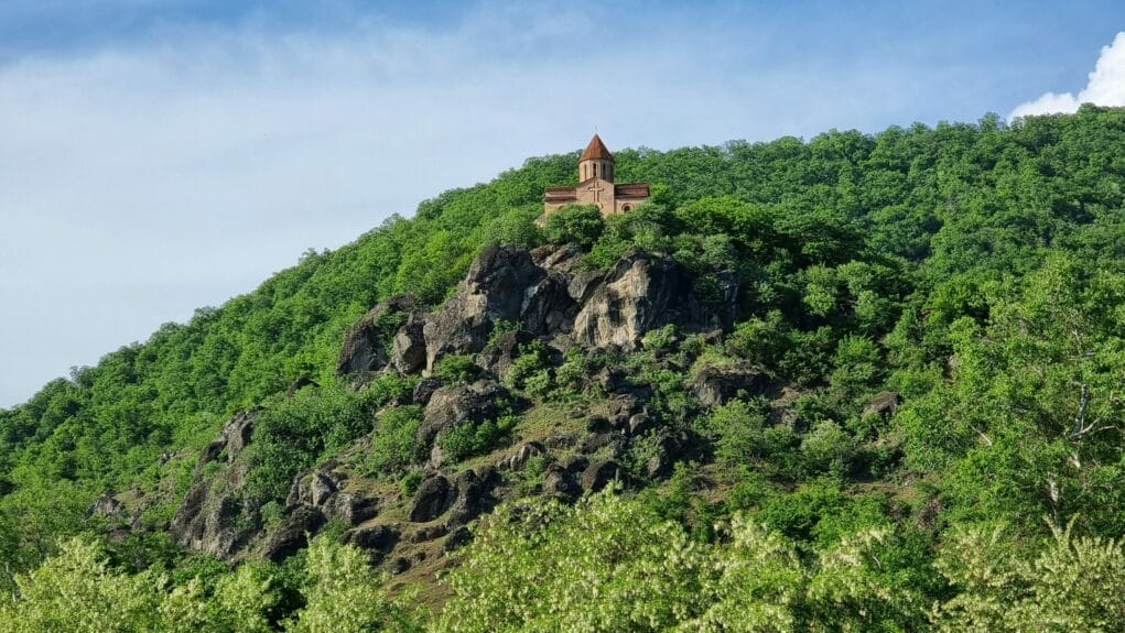 A brown church on top of a mountain under the blue sky in Zaqatala, Azerbaijan.