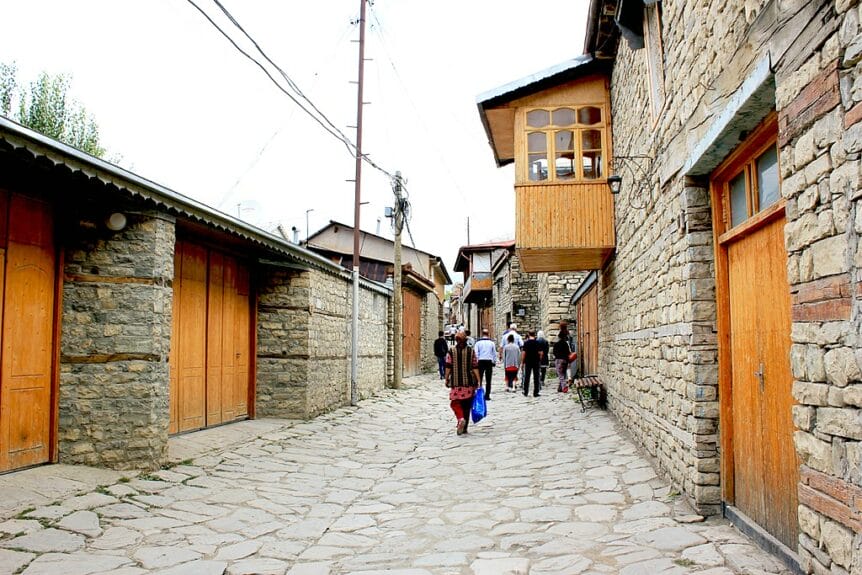 People walking on a street in Lahıc with houses made of stone on both sides of the street in Azerbaijan.