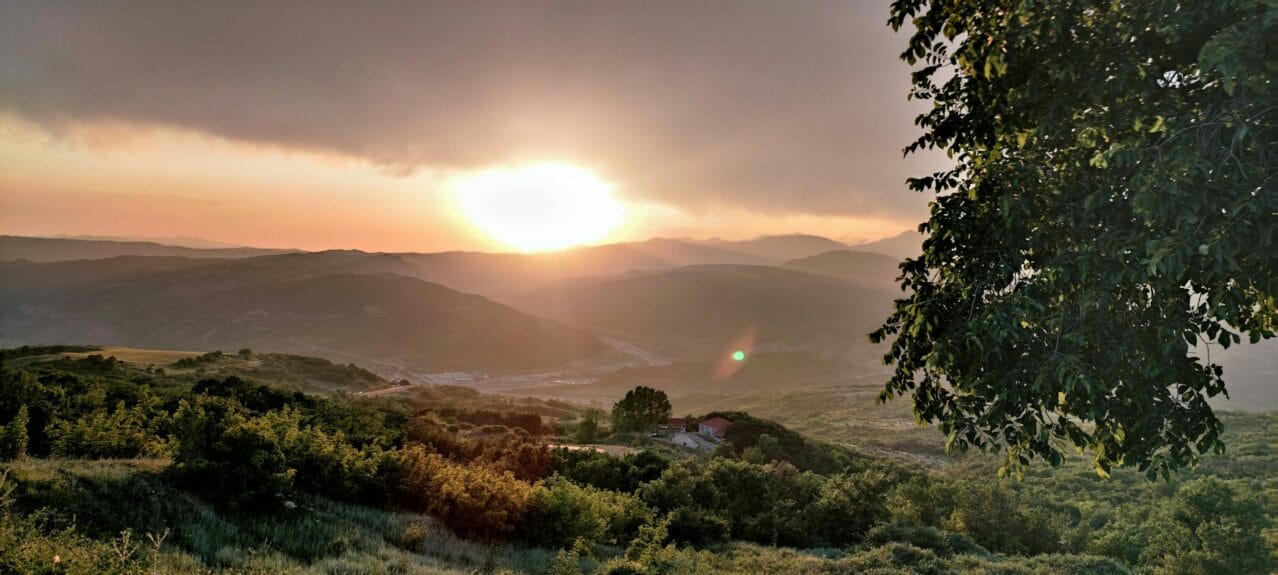 Green trees on a landscape with mountain ranges in the background during sunrise in Shamakhi, Azerbaijan.