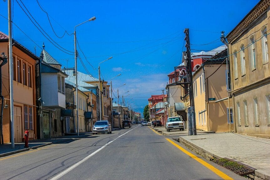 A street in Krasnaya Sloboda with houses and each side and cars parked on sidewalks in Azerbaijan.