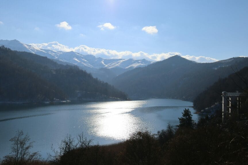 Göygöl Lake surrounded by mountains and trees under a blue sky in Ganja, Azerbaijan.