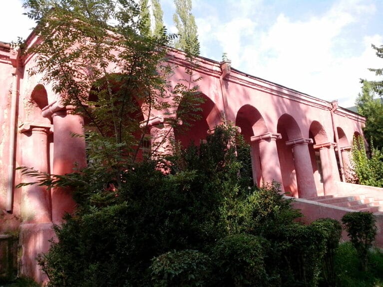 A pink building with trees on the side in Shaki, Azerbaijan.