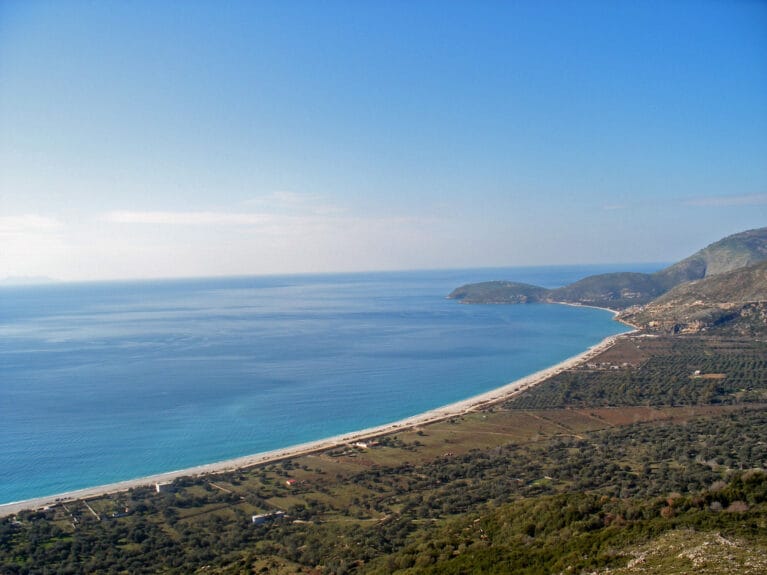 Aerial view of Borsh Beach, Albania, showcasing its long shore and green landscape around it. 