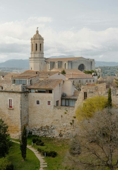 The light brick-walled Santa María de Girona Cathedral with mountains in the background.