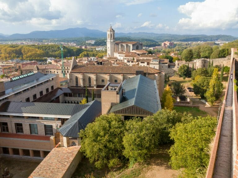 Girona with its towering cathedral, lots of trees, and mountains in the background.