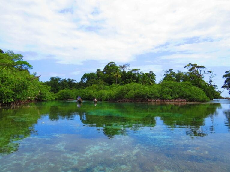 People on a small boat in transparent water channels entering the island of Escudo de Veraguas, Panama.