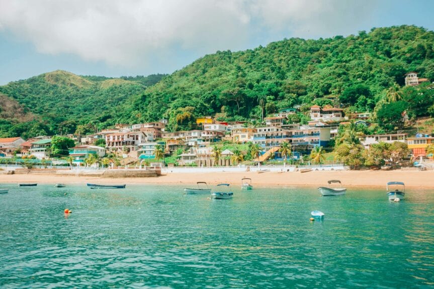 Colorful houses near the beach with lush mountains in the background and boats at the sea in Isla Taboga, Panama