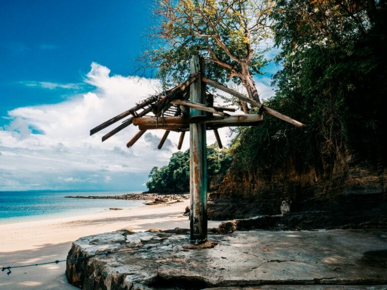 A wrecked wooden hut sitting on top of a sandy beach in Isla Contadora, Panama.