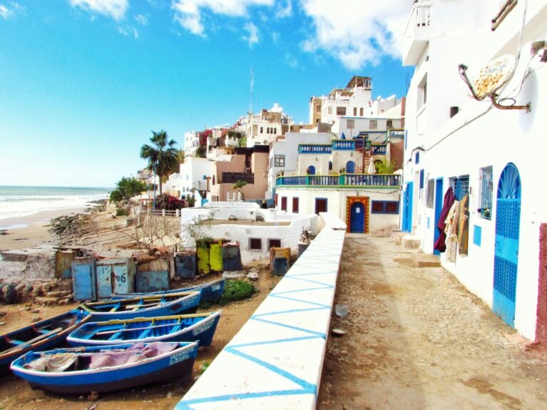 Petits bateaux colorés amarrés près des maisons et d’un plan d’eau à Taghazout, au Maroc.