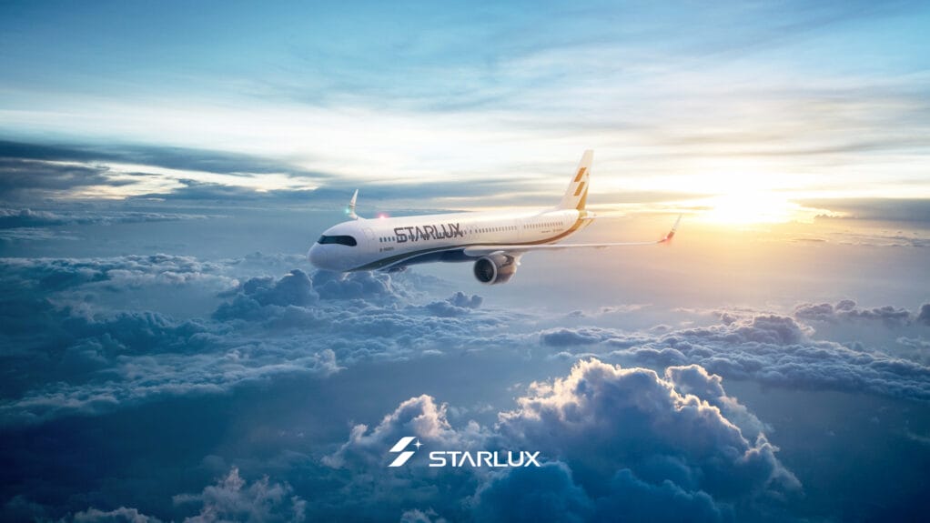 Starlux aircraft in the sky with sunlight breaking through clouds in the background.
