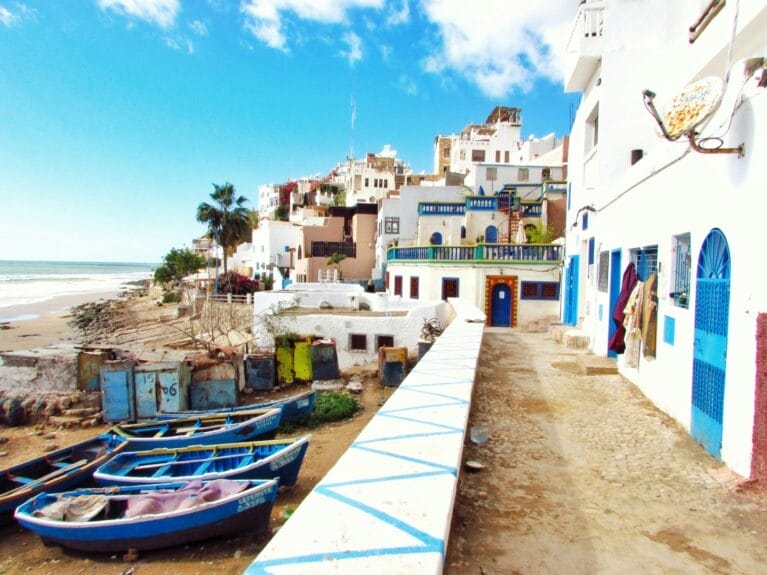 Barquitos coloridos junto a casas en el agua en Taghazout, Marruecos.