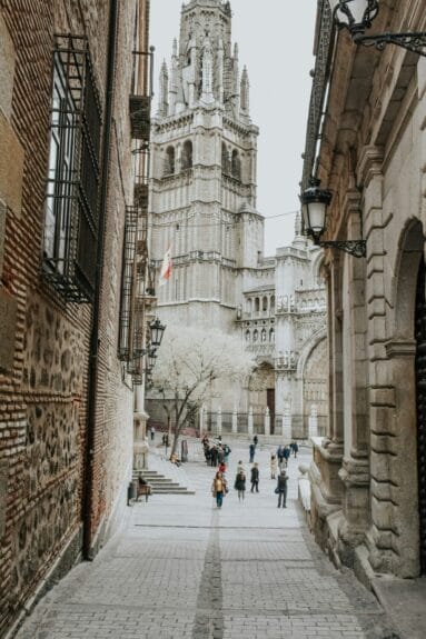 People walking outside exploring the buildings of Toledo, Spain.