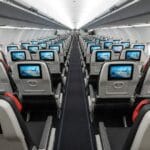 Intérieur d’un avion avec rangées de sièges équipés d’écrans individuels.