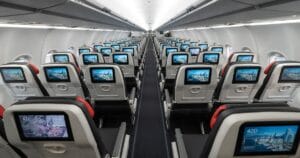 Intérieur d’un avion avec rangées de sièges équipés d’écrans individuels.